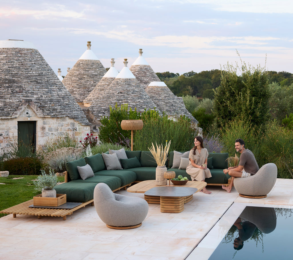 Moderna utomhuslounger med grön sektionell soffa och grå stolar vid en pool.