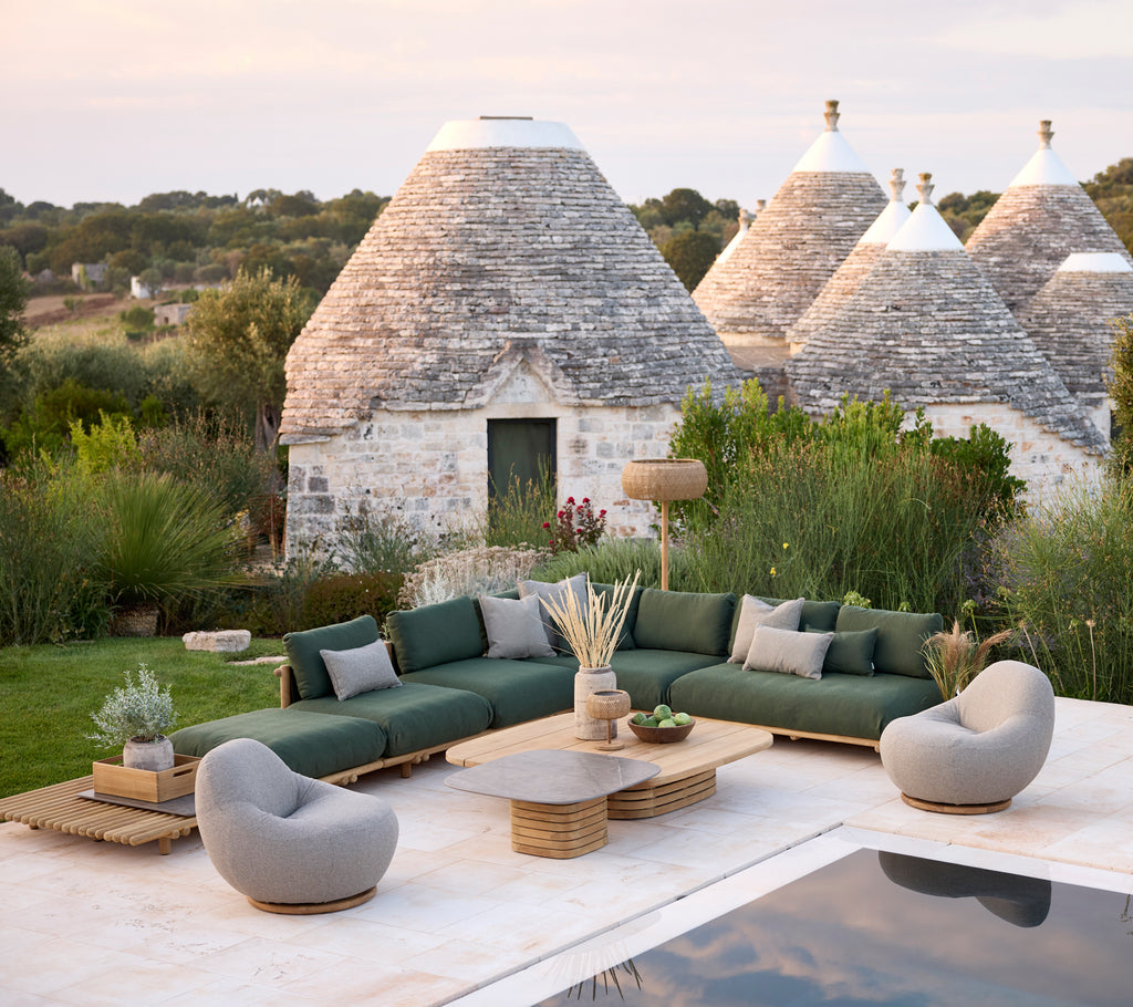 Moderna utomhus loungeområde med grön sektionsoffa, grå fåtöljer och ett bord i trä.