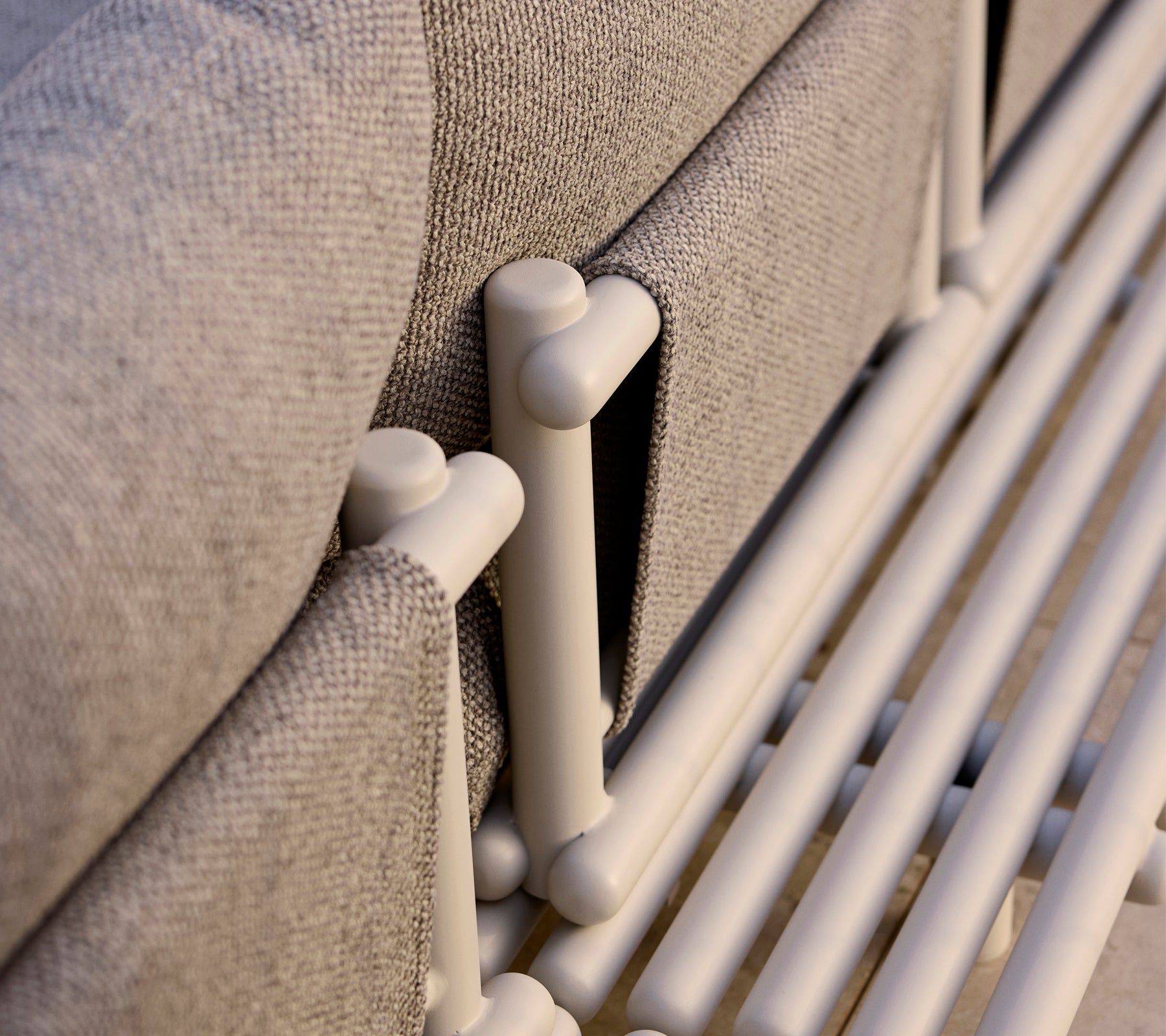 Närbild av en loungeplattform med aluminiumsstänger och ett texturerat grått tyg som framhäver moderna designelement.