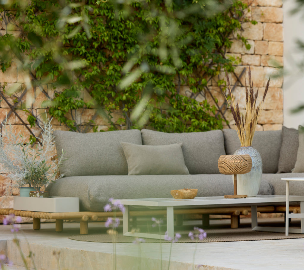 Modern grå soffa med ett träbord i ett stiligt utemöblemang.