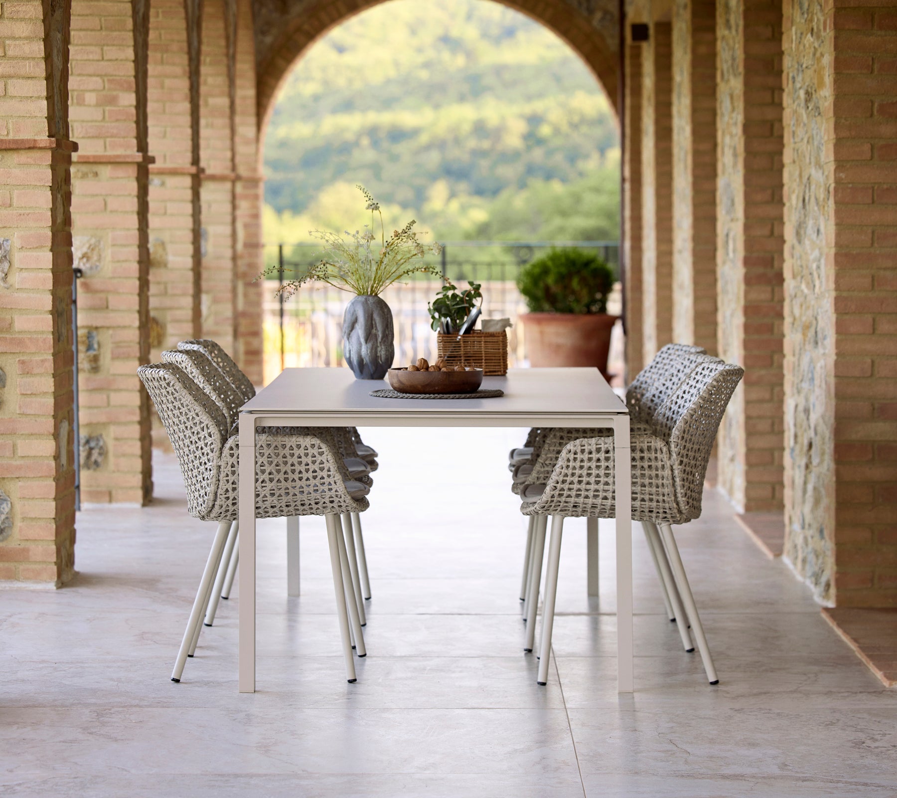 Elegant middagsuppsättning med ett Pure sand matbord omgiven av Vibe matstolar, accentuerat av en vas och dekorativa element.
