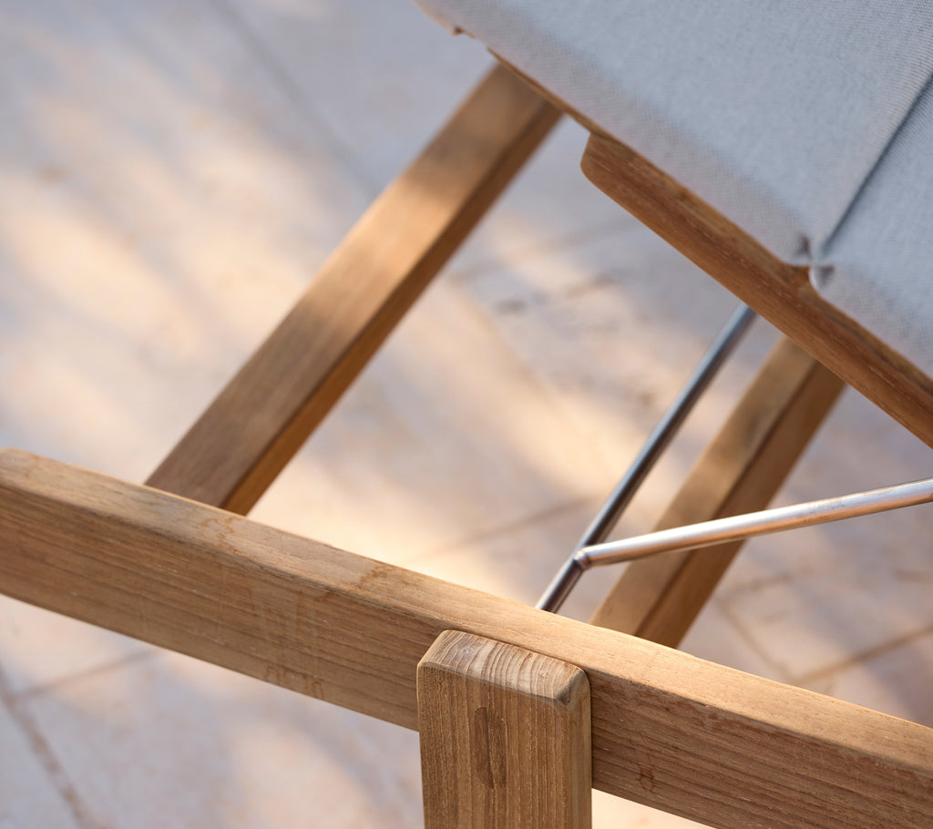 Modern lounge stol med en grå kudde och trästomme.