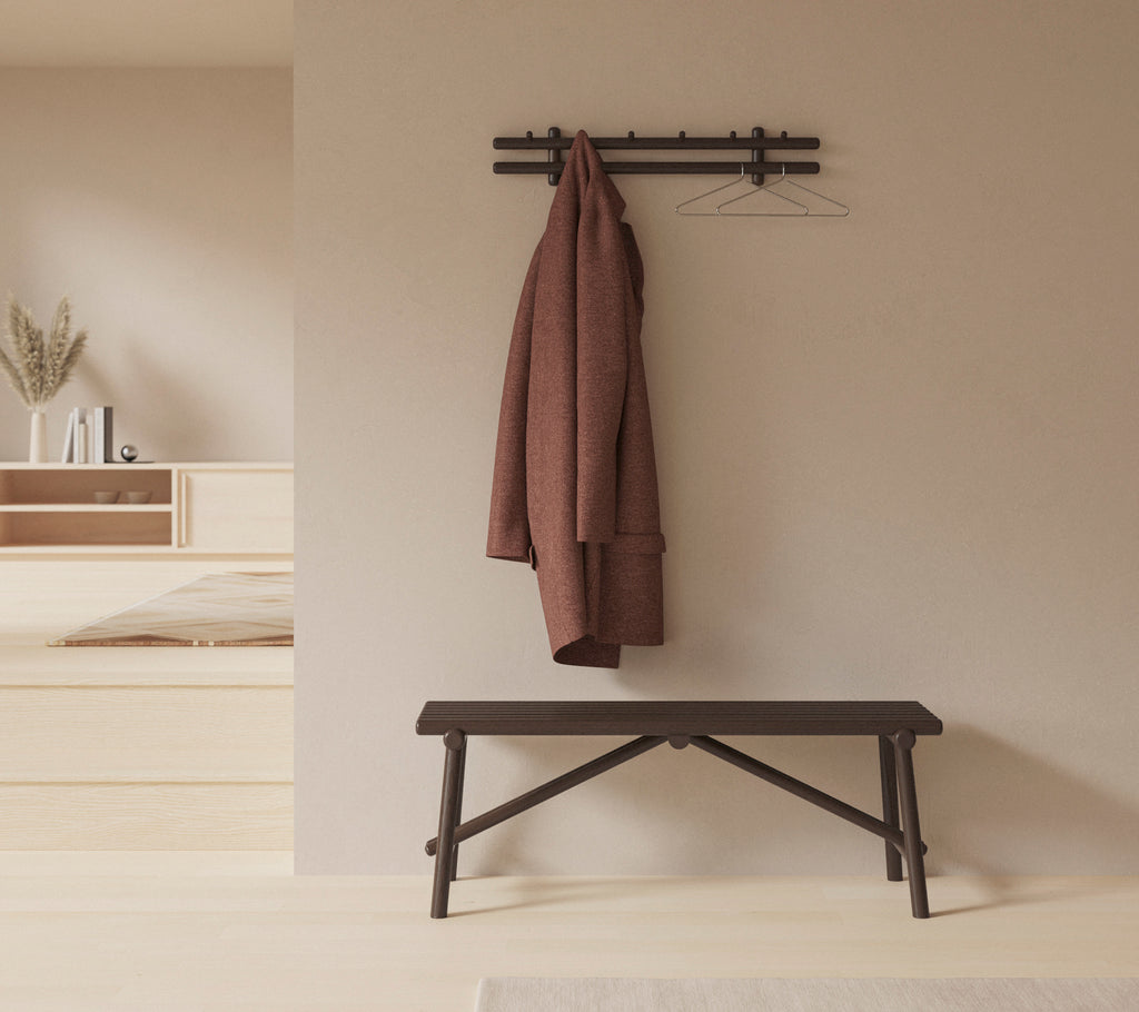 En minimalistisk inredning med en träbänk och en kappa hängande på en väggmonterad hylla, vilket förbättrar rummets enkelhet och funktionalitet.